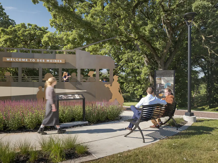 One man and one woman sitting on a park bench in front of Waveland Trolley Loop