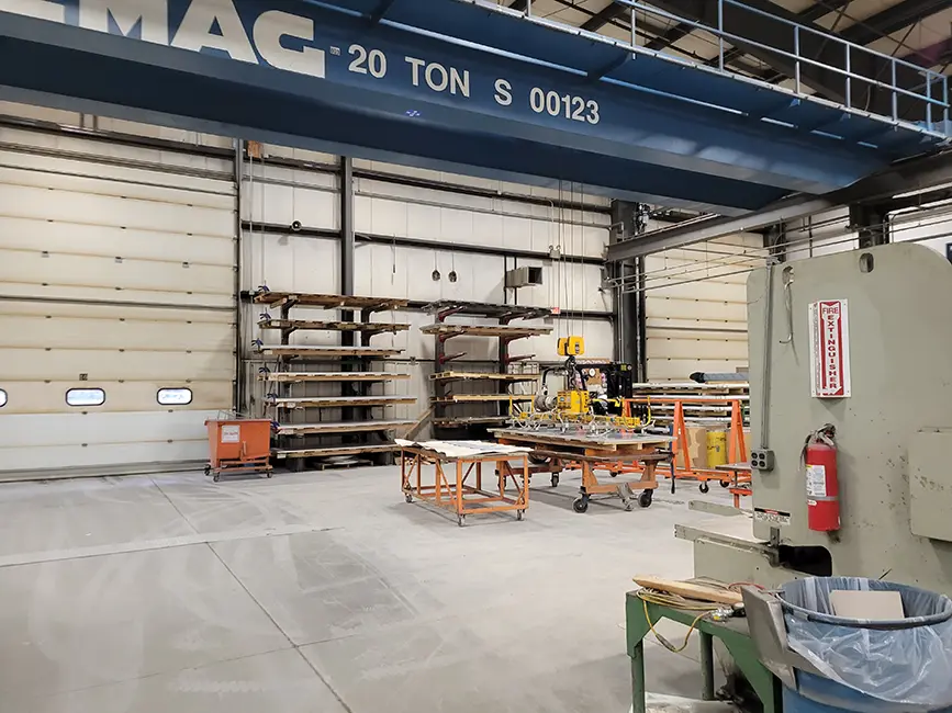 Inside of large industrial manufacturing warehouse with metal machinery, storage, and large dock doors.