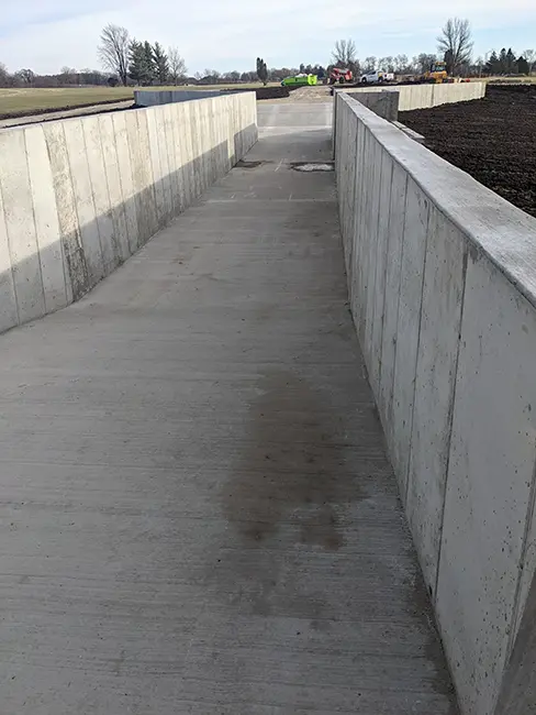 Concrete structure with tall retaining walls on both sides, forming a long channel meant for water testing of equipment.