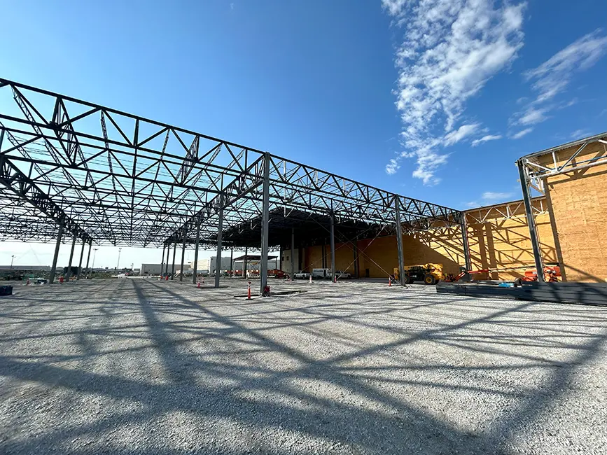 Construction site showing a large steel framework under a clear blue sky.